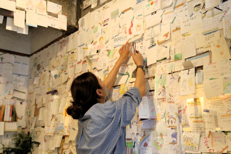 가가책방을 찾은 여행객이 벽면을 가득 메우고 있는 메모를 살펴보고 있다.