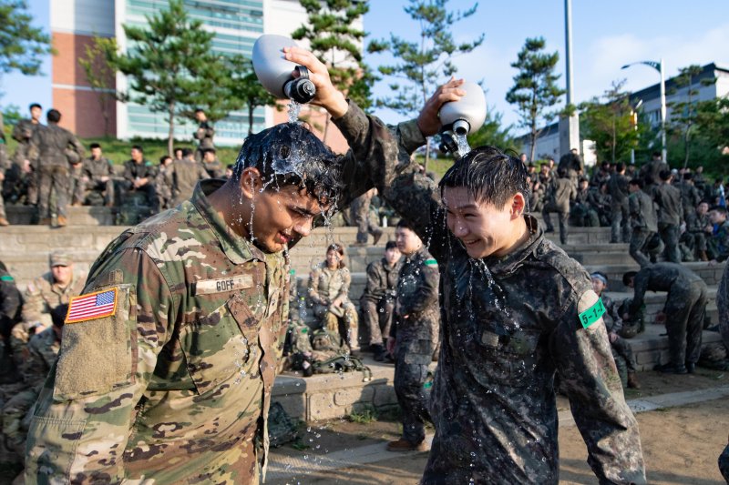 육군이 지난 7일부터 8일 충북 괴산 육군학생군사학교에서 '한미 ROTC 사관후보생 동반훈련'을 실시했다고 8일 밝혔다. 사진은 양국의 후보생들이 서로 수통의 물을 이용해 무더위를 견디고 있는 모습. 육군 제공