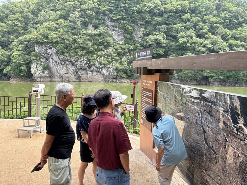 사연댐 수위가 지난 8일 57.26m에 도달하면서 유네스코 세계유산인 울주 대곡리 반구대 암각화 전체가 수면 아래에 잠겨 있다. 반구대 암각화를 찾은 관광객들이 실물 대신 사진을 보면 해설사의 설명을 듣고 있다. 사진=최수상 기자