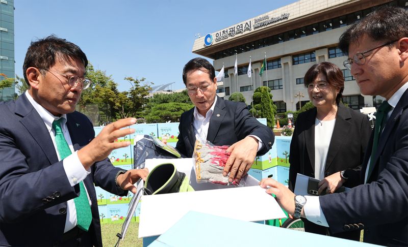 하나금융그룹은 12일 인천시청에서 인천광역시와 지역사회 시니어 일자리 창출과 취약계층 지원을 위한 업무협약을 체결했다. 이날 행사에 참석한 김진우 하나은행 중앙영업그룹 부행장(왼쪽)이 유정복 인천시장(가운데)과 함께 폐지 수거 어르신을 위한 행복상자 구성품을 살펴 보고 있다. 하나은행 제공