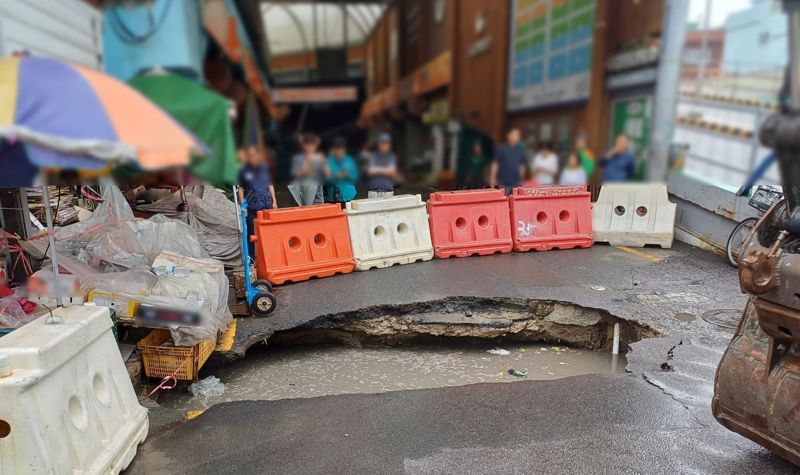 부산 사상구 감전동 새벽시장 입구 바로 앞에 12일 오전 발생한 싱크홀 모습. 시장 상인들과 시민들이 현장을 살펴보고 있다. 부산경찰청 제공