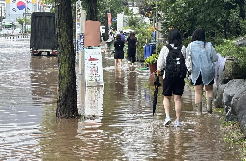 [고양=뉴시스] 홍효식 기자 = 서울을 비롯한 수도권에 호우주의보가 내린 13일 경기 고양시 통일로에서 시민들이 침수된 거리를 걷고 있다. 2025.08.13. yesphoto@newsis.com