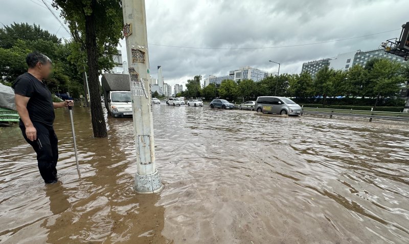 [고양=뉴시스] 홍효식 기자 = 서울을 비롯한 수도권에 호우주의보가 내린 13일 경기 고양시 통일로에서 한 시민이 침수된 도로를 바라보고 있다. 2025.08.13. yesphoto@newsis.com