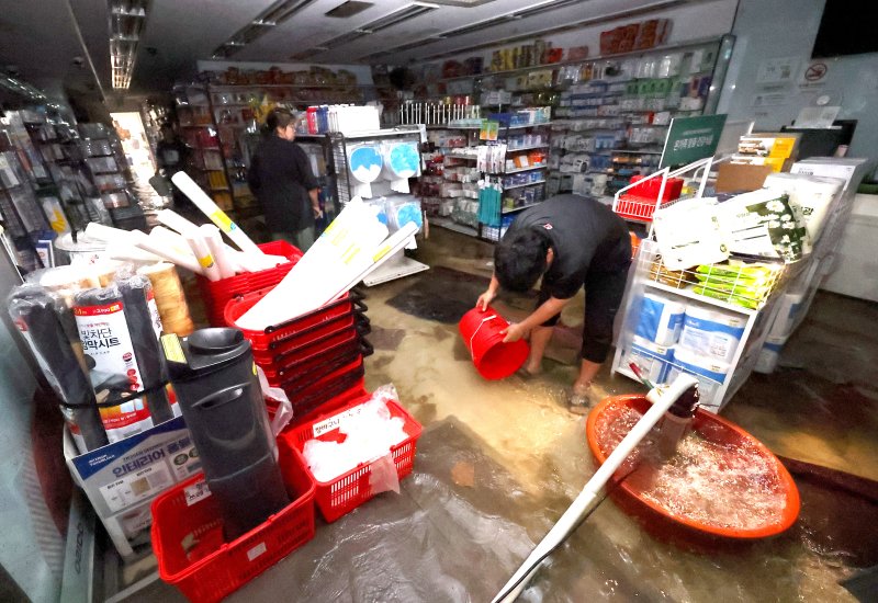 [인천=뉴시스] 전진환 기자 = 13일 오전 간밤에 내린 폭우에 침수된 인천 서구 정서진 중앙시장 한 상가에서 상인이 배수 작업을 하고 있다. 2025.08.13. amin2@newsis.com