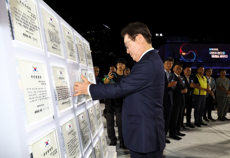 [서울=뉴시스] 고범준 기자 = 이재명 대통령이 15일 서울 세종대로 광화문광장에서 열린 제21대 대통령 국민임명식 '광복 80년, 국민주권으로 미래를 세우다' 행사에서 마지막 임명장을 받은 뒤 거치하고 있다. 2025.08.15. bjko@newsis.com