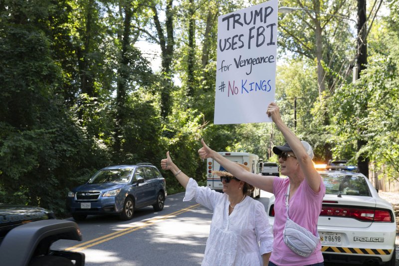 [베데스다=AP/뉴시스] 22일(현지 시간) 미 메릴랜드주 베데스다에서 미 연방수사국(FBI) 요원들이 존 볼턴 전 백악관 국가안전보장회의(NSC) 보좌관 자택을 압수수색하는 동안 인근 주민으로 보이는 사람들이 이를 조롱하는 손팻말을 들고 있다. 2025.08.24.