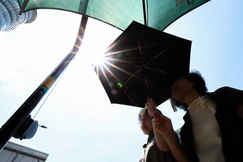 전국 대부분 지역에 폭염특보가 발효된 지난 21일 서울 종로구 광화문광장 인근에서 시민들이 그늘막 아래서 햇빛을 피하며 신호를 기다리고 있다. 뉴시스
