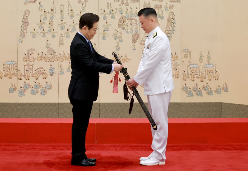 [서울=뉴시스] 최동준 기자 = 이재명 대통령이 2일 서울 용산 대통령실 청사에서 열린 대장 진급·보직 신고 및 삼정검 수치 수여식에서 강동길 해군참모총장의 삼정검에 수치를 달아주고 있다. (대통령실통신사진기자단) 2025.09.02. photocdj@newsis.com