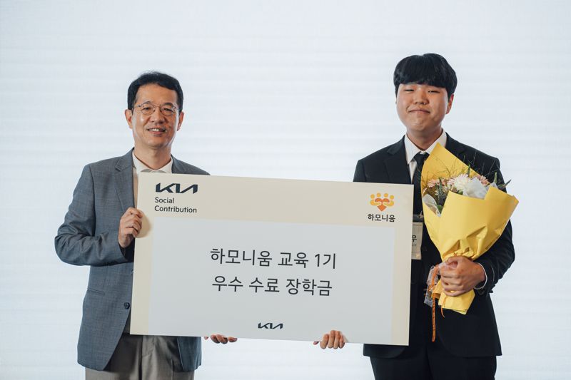 기아 지속가능경영실장 이덕현 상무(왼쪽)가 지난 7일 서울 영등포구 콘래드 호텔에서 열린 '하모니움 교육 프로그'램 1기 수료생 오민우 학생에게 우수 수료생 시상을 한 뒤 기념촬영을 하고 있다. 기아 제공