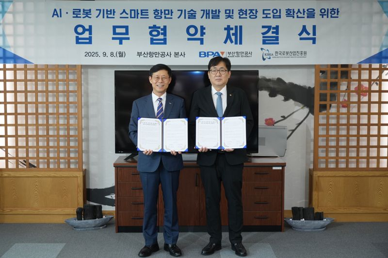 부산항만공사 송상근 사장(왼쪽)과 한국로봇산업진흥원 류지호 원장 직무대행이 8일 BPA 사옥에서 ‘AI·로봇 기반 스마트항만 기술 개발 및 현장 실증 확산을 위한 업무협약’을 체결하고 기념촬영을 하고 있다. 공사 제공