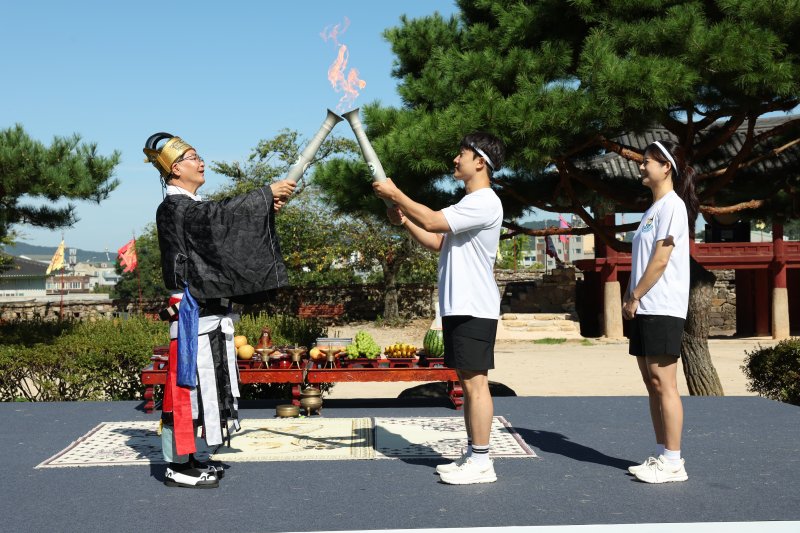 제62회 전북특별자치도민체육대회를 하루 앞둔 11일 심덕섭 고창군수(왼쪽)가 봉송 첫 주자인 신혼부부에게 성화를 전달하고 있다. 고창군 제공