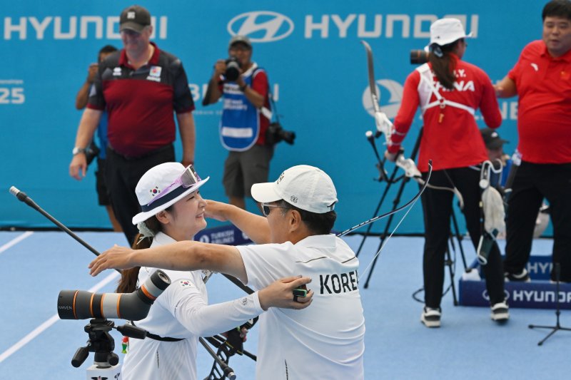 [광주=뉴시스] 이영주 기자 = 12일 오후 광주 동구 5·18민주광장에서 열린 광주2025현대세계양궁선수권대회 리커브 여자 개인전 금메달 결정전, 대한민국 국가대표 강채영(현대모비스)이 중국 국가대표 주징이(Zhu Jingyi)를 상대로 승리를 거둔 뒤 감독과 포옹하고 있다. 대한민국 대표팀 뒤로 중국 대표팀이 서로를 격려하고 있다. 2025.09.12. leeyj2578@newsis.com