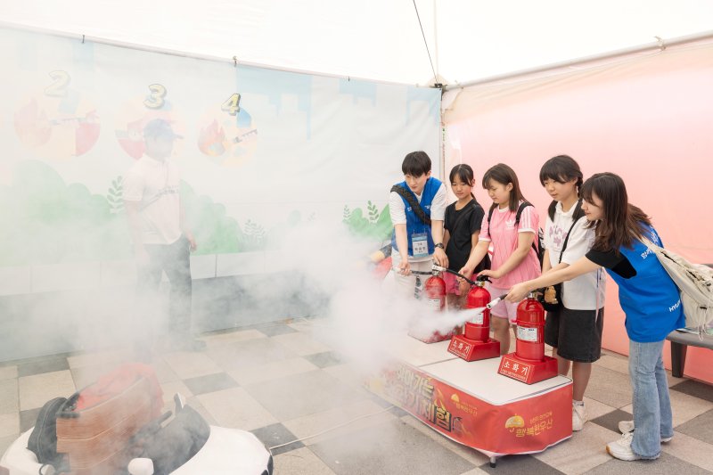 현대글로비스가 지난 6월 서울대공원 인근에 마련한 '물류 이동 안전 체험존'에서 임직원과 어린이들이 소화기를 이용한 가상 화재 진압 체험을 하고 있다.