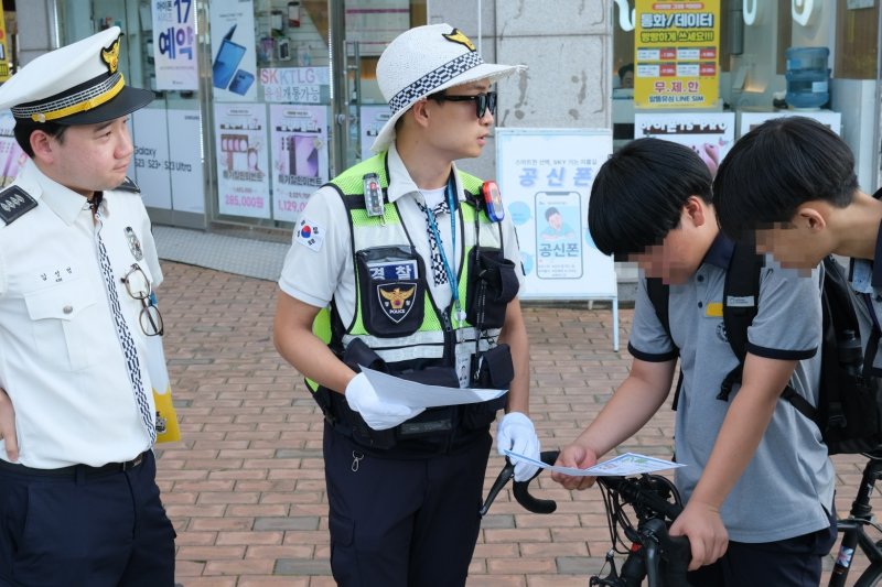 15일 오후 서울 강동구 고덕역 인근에서 김성현 강동경찰서 교통안전계 경장이 나눠준 안내문을 아이들이 유심히 읽어보고 있다. 2025.09.15/ⓒ 뉴스1 이정환 기자