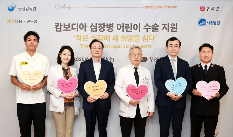 KB국민은행이 심장병을 앓고 있는 캄보디아 어린이 5명을 국내로 초청해 경기도 부천 세종병원에서 무료 수술 및 의료 지원을 실시한다. 17일 세종병원에서 진행된 병문안 행사에서 나마디 조엘 진 육상선수, 정현 세종병원 소아청소년과장, 이환주 KB 국민은행장, 이명묵 세종병원장, 이세훈 금융감독원 수석부원장, 한세종 구세군 한국군국 서기장관(왼쪽부터)이 기념촬영을 하고 있다./사진=KB국민은행