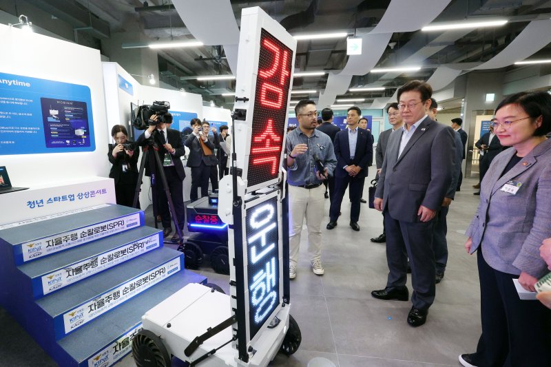 이재명 대통령이 17일 경기도 성남시 스타트업 스퀘어에서 스타트업 전시 부스를 방문해 자율주행 순찰 로봇 시연을 관람하고 있다. 뉴시스