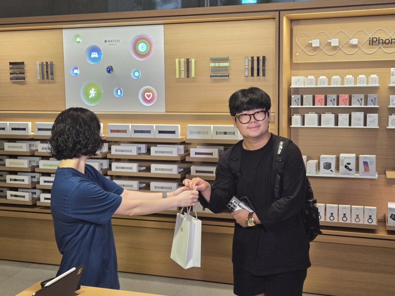 [서울=뉴시스]19일 애플 명동의 아이폰17 시리즈 1호 구매자인 김지민(20대) 씨가 애플스토어 직원에게 새로 구매한 아이폰 에어를 건네받고 있다. (사진=윤현성 기자)