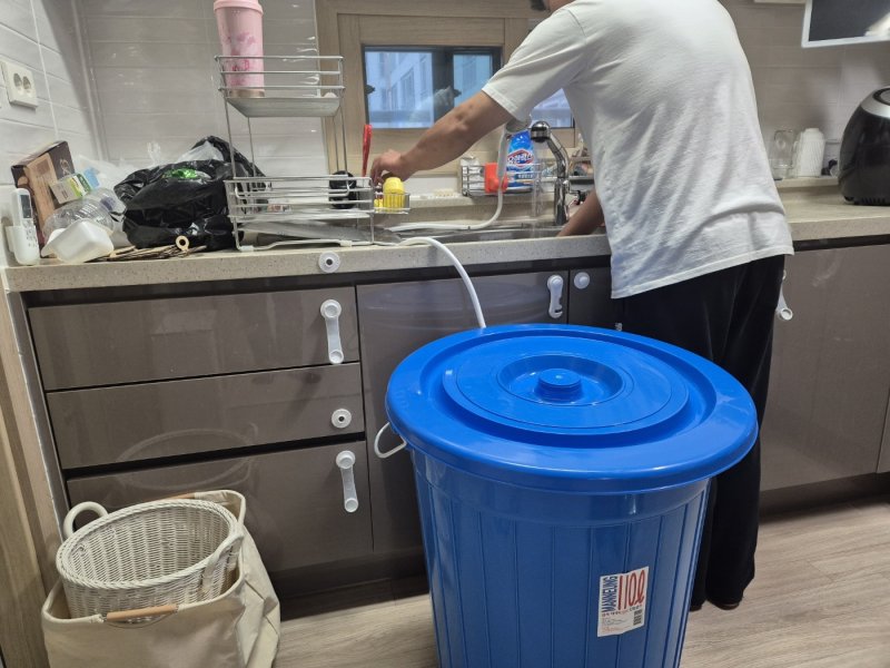 강원 강릉지역 저수조 용량 100톤 이상 아파트 113곳에 대한 시간제 제한급수가 풀린 19일 저녁 강릉 회산동의 한 아파트 주민이 수돗물을 이용해 설거지를 하고 있다. 싱크대 근처에 그동안 물을 아끼려고 달아놓은 샤워헤더와 물통이 놓여 있다.2025.9.19/뉴스1 ⓒ News1 윤왕근 기자