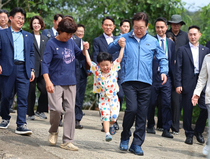 [세종=뉴시스] 고범준 기자 = 이재명 대통령이 16일 세종시 전동면 조일농원에서 박성호 조일농원 대표 가족의 손을 잡고 청년 농업인 간담회장으로 이동하고 있다. (대통령실통신사진기자단) 2025.09.16. bjko@newsis.com