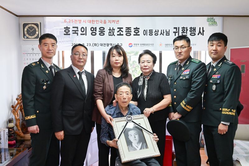 국유단 관계자들과 유가족이 기념사진을 촬영하고 있다. 가운데가 고인의 생전 사진을 들고 있는 고인의 아들 조정원 씨. 국방부 제공