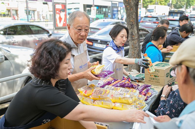 류진 한국경제인협회 회장(왼쪽 두 번째)이 1일 서울 영등포에 있는 무료급식소 '토마스의 집'을 찾아 빵 등 간식거리를 나눠주고 있다. 한경협 제공