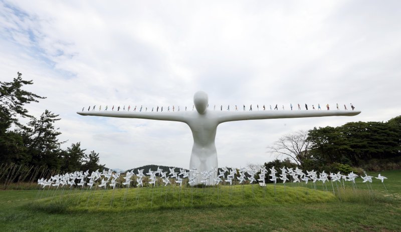 산이정원 하늘마루에 설치된 유영호 작가의 거대 조각상 '브리지 오브 휴먼'. 몸을 숙여 스스로 다리 역할을 하는 거인의 두 팔 위에 42명의 인간 군상이 보인다. 사진=박범준 기자