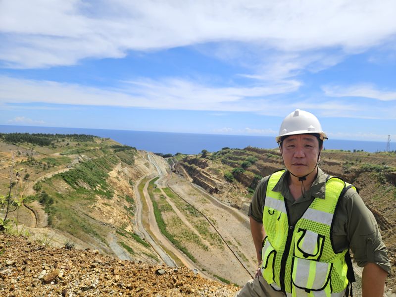 이준택 LX인터내셔널 마닐라 지사장이 필리핀 라푸라푸 광산 복구 프로젝트 현장을 배경으로 서 있다. 2018년부터 2023년까지 진행된 프로젝트의 중반기로, 황무지였던 땅이 풀기어린 땅으로 변모해 있다. LX인터내셔널 제공