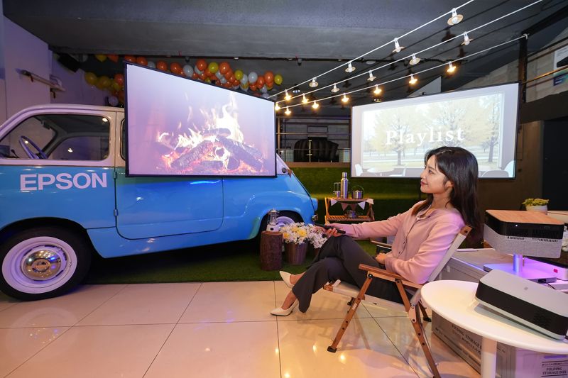 한국엡손 모델이 21일 서울 봉은사로 JBK컨벤션홀에서 열린 홈프로젝터 신제품 발표회에서 캠핑존 컨셉으로 꾸며진 체험 공간에 마련된 엡손 미니 프로젝터 ‘EF-61G’, ‘EF-72’를 소개하고 있다. 한국엡손 제공