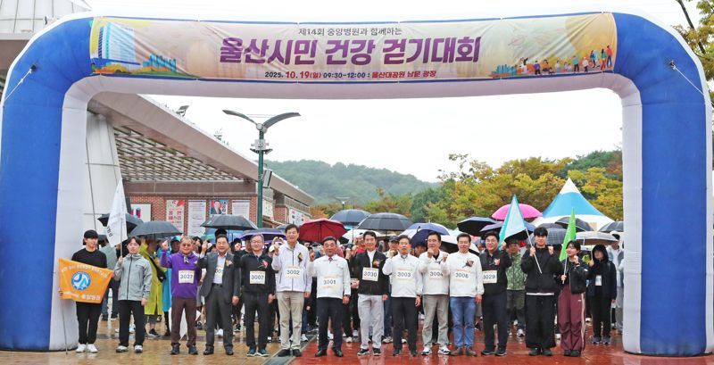 지난 19일 비가 내리는 가운데 열린 중앙병원 울산시민 건강걷기대회 모습. 내빈 뒤쪽 참가자들이 우산을 받쳐 든 채 기념촬영을 지켜보고 있다. 울산시 제공