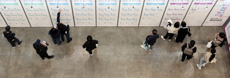 [부산=뉴시스] 하경민 기자 = '2025 부산 잡(JOB) 페스티벌'이 열린 27일 부산 해운대구 벡스코 제1전시장에서 구직자들이 채용기업 현황판을 둘러보고 있다. 이날 행사에는 공공기관 10곳을 포함한 기업 총 215곳이 참가해 구직자를 상대로 현장 면접, 채용 상담 등을 진행했다. 또 채용관, 홍보관, 컨설팅관, 체험관, 취업특강·기업설명회, 부대행사 등 다양한 프로그램을 운영했다. 2025.10.27. yulnetphoto@newsis.com