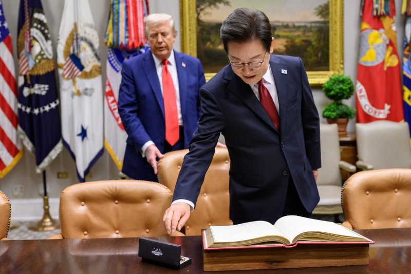 지난 8월 25일(현지시간) 이재명 대통령이 한미정상회담에 앞서 미 백악관 루즈벨트룸에서 방명록에 서명하려고 펜을 잡으려는 순간 도널드 트럼프 미국 대통령이 뒤에서 의자를 당겨 주고 있다. (백악관 제공. 재판매 및 DB금지) 2025.9.1/뉴스1 ⓒ News1 류정민 특파원