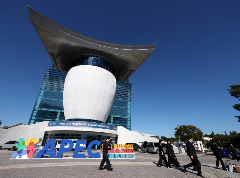 [경주=뉴시스] 추상철 기자 = 2025 APEC CEO 서밋을 하루 앞둔 27일 오후 경북 경주시 경주예술의전당 앞에서 부스 관계자가 행사 로고 앞을 지나고 있다. 2025.10.27. scchoo@newsis.com