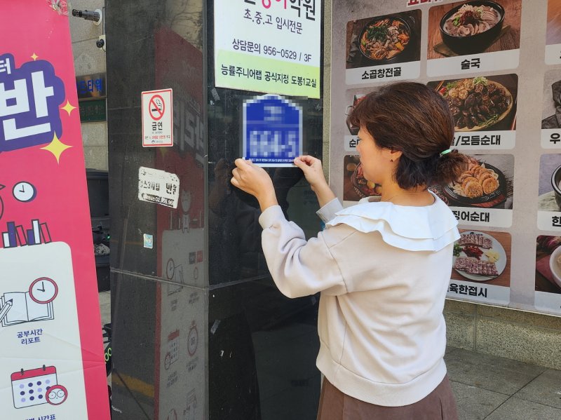 [서울=뉴시스] 도봉구 직원이 도로명주소표지판에 큐싱사기 방지 안내 문구 스티커를 부탁하고 있다. 2025.10.29. (사진=도봉구 제공) *재판매 및 DB 금지