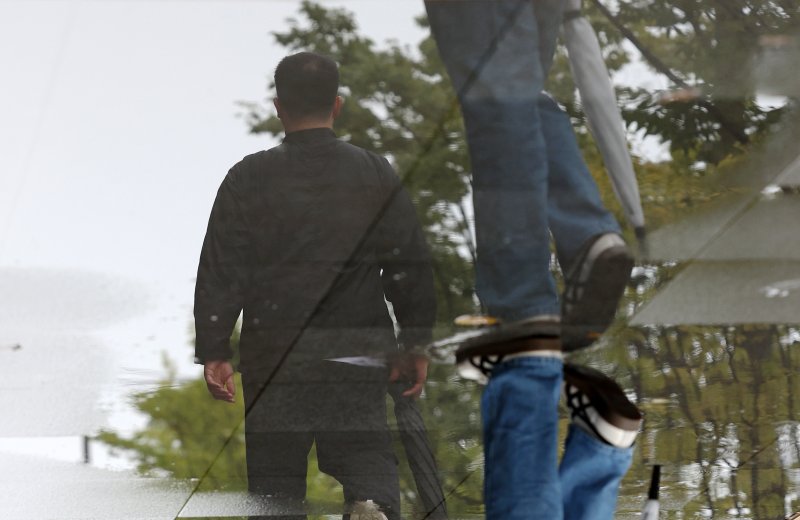 [서울=뉴시스] 조성우 기자 = 비가 내리는 14일 오전 서울 종로구 세종대로 인근에서 인도에 고인 빗물에 이동하는 시민의 모습이 비치고 있다. 2025.10.14. xconfind@newsis.com