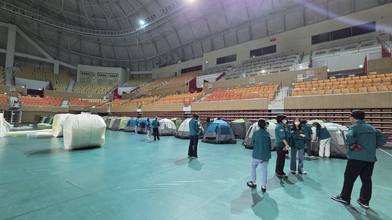 [광주=뉴시스] 박기웅 기자 = 17일 오전 광주 광산구 소촌동 금호타이어 광주공장 화재 현장에서 발생한 검은 연기와 유독가스가 인근 주택가로 퍼지자 행정 당국이 대피소를 마련하고 있다. 이날 광산구는 광주여자대학교 체육관에 400세대가 머무를 수 있는 텐트를 설치할 예정이다. (사진 = 광주 광산구 제공) 2025.05.17. photo@newsis.com *재판매 및 DB 금지