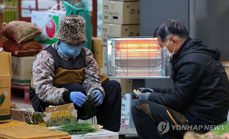 난로에 몸 녹이는 상인들 (출처=연합뉴스)