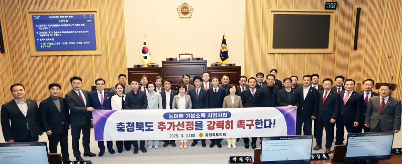 [청주=뉴시스] 충북도의원들이 3일 도의회 제430회 정례회 1차 본회의에서 '농어촌 기본소득 시범사업 충북 추가 선정 및 국비 지원 상향 촉구' 대정부 건의문 채택 후 기념 촬영하고 있다.(사진=충북도의회 제공) 2025.11.03. photo@newsis.com *재판매 및 DB 금지
