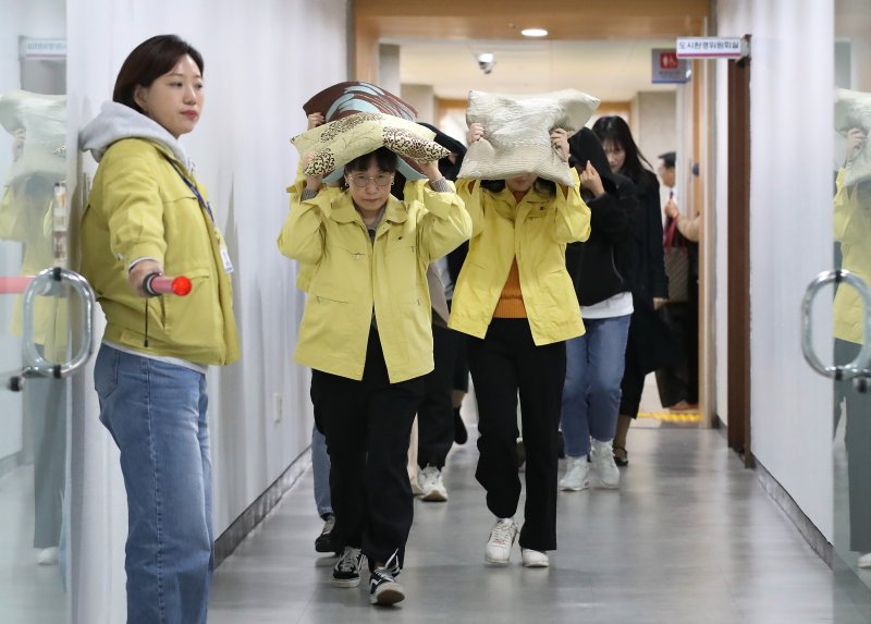 대구 달서구청에서 지진 발생 상황을 가정해 열린 대피 훈련에서 구청 직원들이 지진 대피 안내방송에 따라 방석으로 머리를 보호하며 인근 대피소로 이동하고 있다. 2025.10.28/뉴스1 ⓒ News1 공정식 기자
