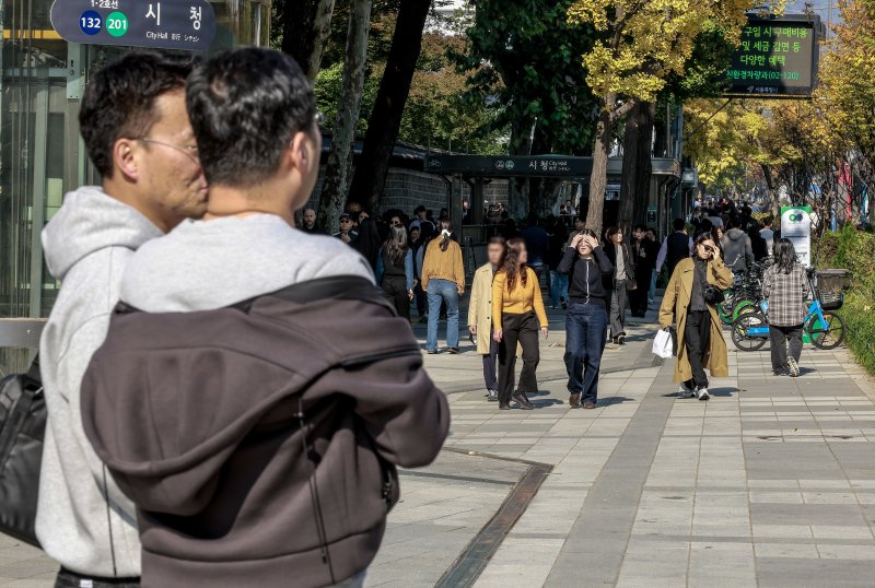 [서울=뉴시스] 정병혁 기자 = 완연한 가을 날씨를 보인 4일 서울 중구 덕수궁 인근에서 겉옷을 벗은 시민이 신호를 기다리고 있다. 2025.11.04. jhope@newsis.com