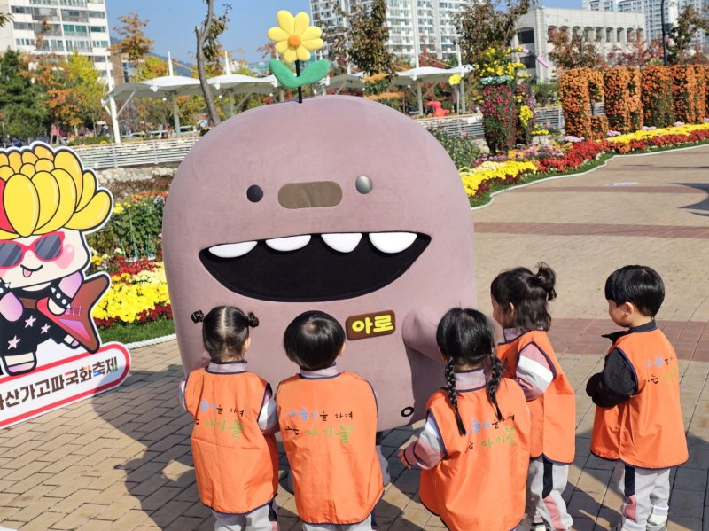 [창원=뉴시스] 강경국 기자 = 경남 창원시 관광 캐릭터 '아로'(아구+로봇)가 제25회 마산가고파국화축제장에서 어린이들로부터 인기를 끌고 있다. (사진=창원시청 제공). 2025.11.05. photo@newsis.com *재판매 및 DB 금지