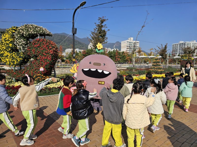 [창원=뉴시스] 강경국 기자 = 경남 창원시 관광 캐릭터 '아로'(아구+로봇)가 제25회 마산가고파국화축제장에서 어린이들로부터 인기를 끌고 있다. (사진=창원시청 제공). 2025.11.05. photo@newsis.com *재판매 및 DB 금지