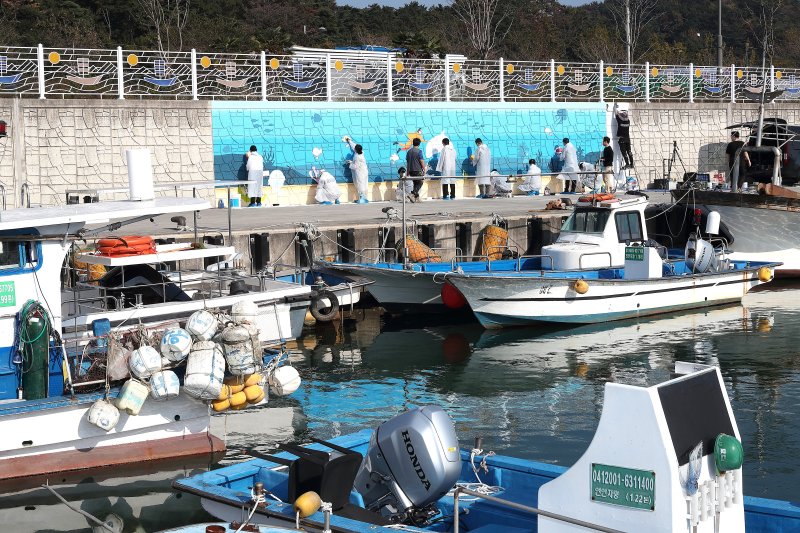 [울산=뉴시스] 한국석유공사 임직원들이 5일 울주군 강양항 선착장에서 어촌마을 벽화 그리기 봉사 활동을 하고 있다. (사진=한국석유공사 제공) 2025.11.05. photo@newsis.com *재판매 및 DB 금지
