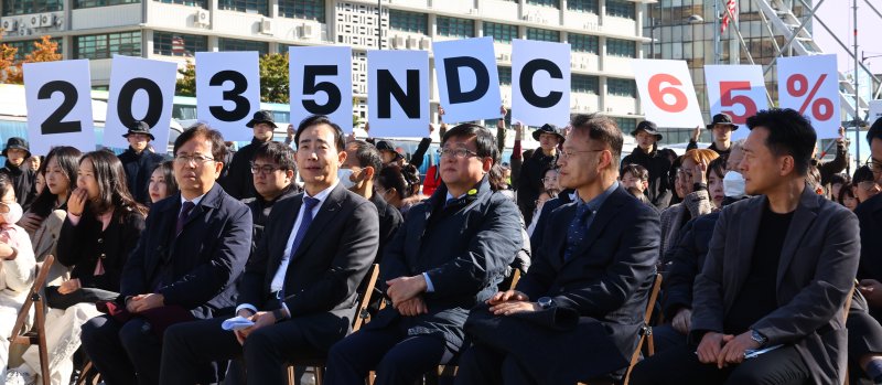 [서울=뉴시스] 박주성 기자 = 지난달 27일 서울 광화문광장에서 김성환 기후에너지환경부 장관(앞줄 오른쪽에서 세번째)이 참석한 제3회 지구하다 페스티벌 개막식에서 기후위기비상행동 회원들이 2035년 국가 온실가스 감축목표(NDC) 65% 수립을 촉구하는 피켓을 들어보이고 있다. 2025.10.27. park7691@newsis.com