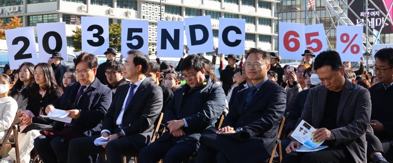 [서울=뉴시스] 박주성 기자 = 지난달 27일 서울 광화문광장에서 김성환 기후에너지환경부 장관(앞줄 오른쪽에서 세번째)이 참석한 제3회 지구하다 페스티벌 개막식에서 기후위기비상행동 회원들이 2035년 국가 온실가스 감축목표(NDC) 65% 수립을 촉구하는 피켓을 들어보이고 있다. 2025.10.27. park7691@newsis.com