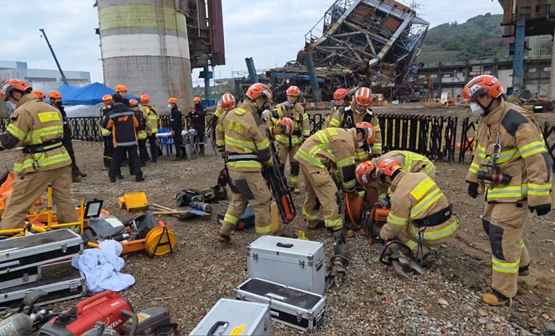 9일 새벽 구조 수색작업에 나서기 위해 구조대원들이 장비를 준비 중이다. 구조대원들 뒤로 지난 6일 무너진 한국동서발전 울산화력발전 보일러 타워 5호기가 보인다. 구조대원들은 이날 오전 11시 5분께 매몰 희생자 시신 1구를 수습해 병원으로 이송했다. 사고 발생 나흘째인 이날까지 사망이 확인된 매몰자는 3명이며, 사망 추정 2명, 실종 2명 상태다. 울산소방본부 제공