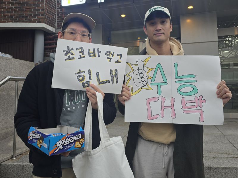 2026학년도 대학수학능력시험(수능) 당일인 13일 오전 서울 종로구 경복고등학교 앞에서 황모씨(35, 왼쪽)가 지인 왈리씨(40)와 수험생들을 응원하고 있다. 사진=서지윤 기자