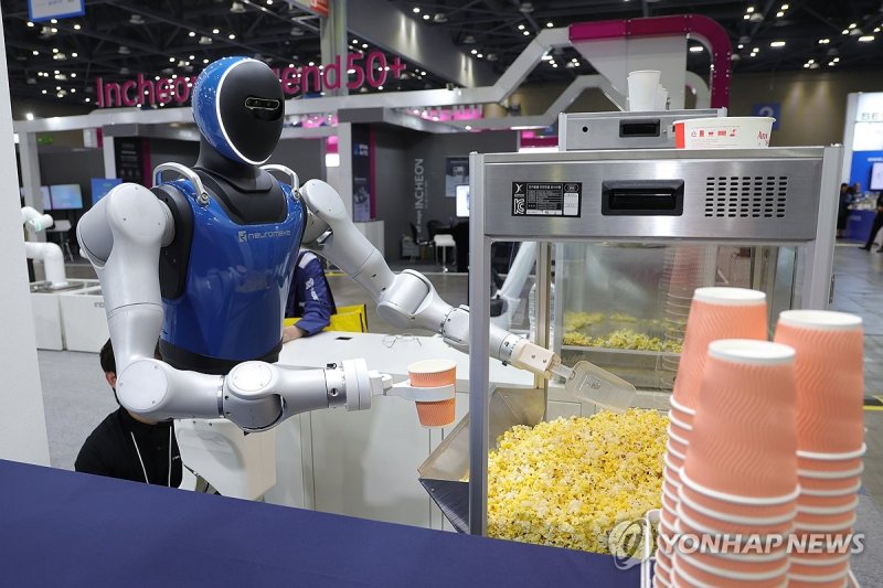 휴머노이드 로봇이 관람객의 주문에 팝콘을 담고 있다. 연합뉴스