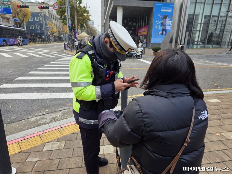 25일 오후 서울 동대문구 한국외국어대학교 정문 앞에서 박모씨가 헬멧 미착용으로 적발돼 범칙금 통고를 받고 있다. 사진=박성현 기자