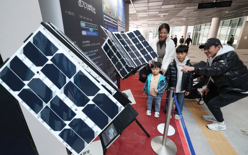 ‘경기기후위성’ 1호기 발사를 하루 앞둔 25일 경기 수원시 영통구 경기신용보증재단 도민쉼터에 마련된 경기기후위성 임시상황실에서 시민들이 '경기기후위성' 모형을 살펴보고 있다. ⓒ News1 김영운 기자