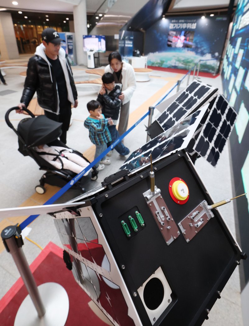 ‘경기기후위성’ 1호기 발사를 하루 앞둔 25일 경기 수원시 영통구 경기신용보증재단 도민쉼터에 마련된 경기기후위성 임시상황실에서 시민들이 '경기기후위성' 모형을 살펴보고 있다. ⓒ News1 김영운 기자